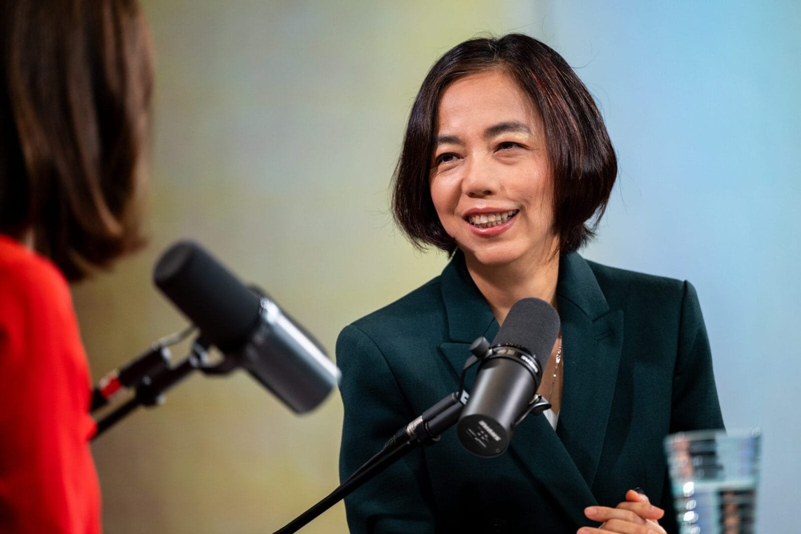 Fei-Fei Li speaking at a conference, with a cityscape in the background.