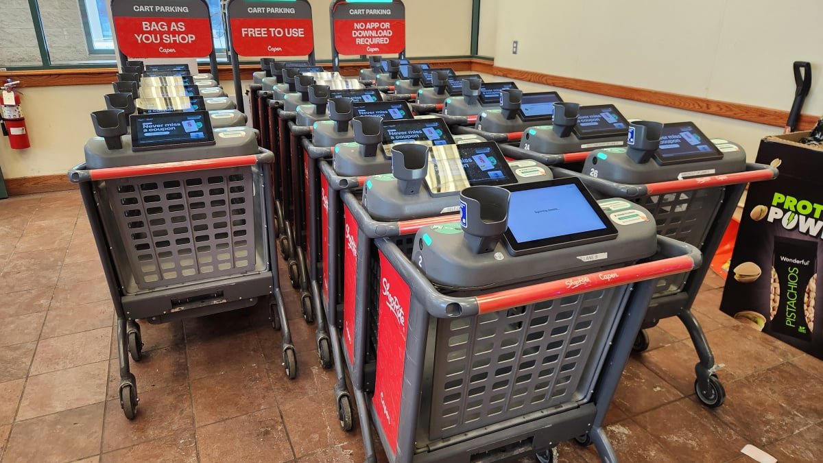 Navigating the Future Aisle: A Journalist's Hands-On with AI Shopping Carts 3 A Caper AI shopping cart with a digital screen displaying product information in a grocery store aisle.
