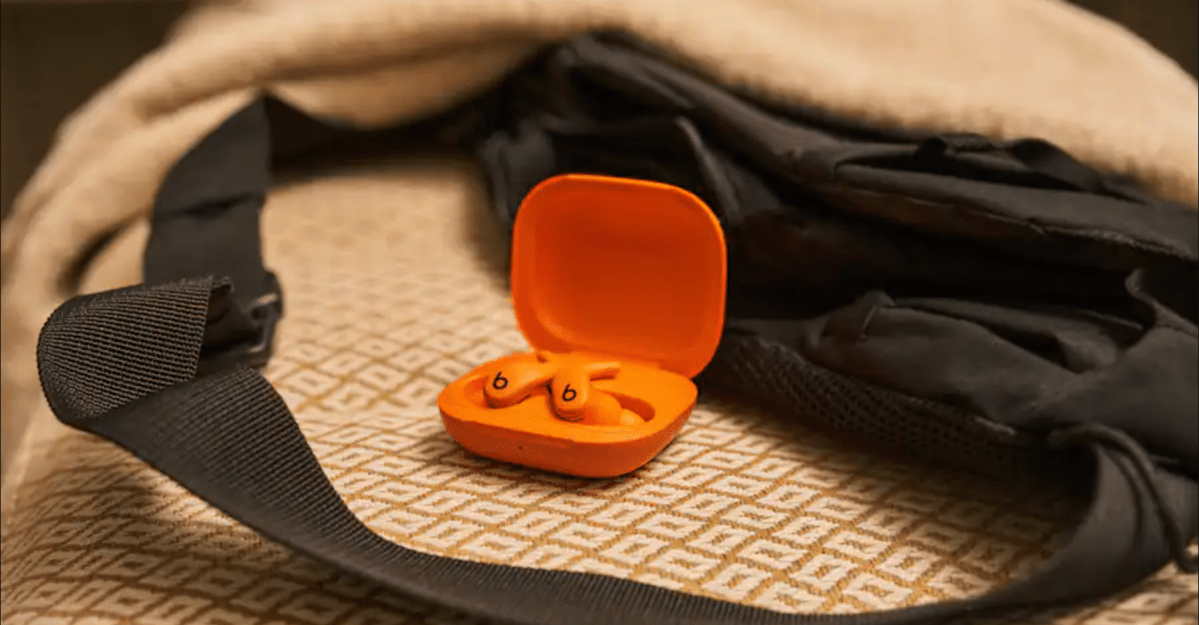 Beats Powerbeats Fit earbuds in their charging case, alongside a Google Pixel Watch 4 and an Apple Pencil Pro.