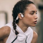 Casque Shokz OpenMove avec un sportif en train de courir sous la pluie.
