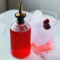 Fresh cranberries and orange peel on a wooden cutting board.