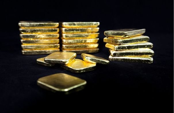 قضبان ذهبية لامعة مع رسم بياني يظهر انخفاضاً في الأسعار، تعكس تراجع قيمة المعدن النفيس عالمياً.