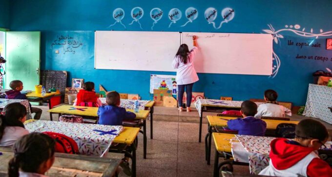 صورة لطلاب يخرجون من المدرسة في يوم جاف، مع خلفية من السحب العميقة.