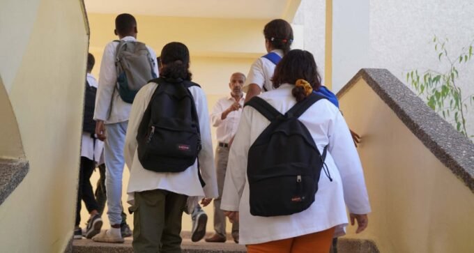 صورة لطفل يرتدي قميصًا ويحمل لوحة تعليمية في المدرسة.