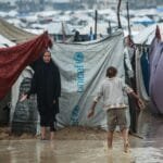 صورة لأحد الأطفال يلجأ إلى الخيمة المصابة بالمياه.