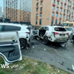 صورة سيارة بيضاء متضررة بشدة في موقف السيارات في موسكو.