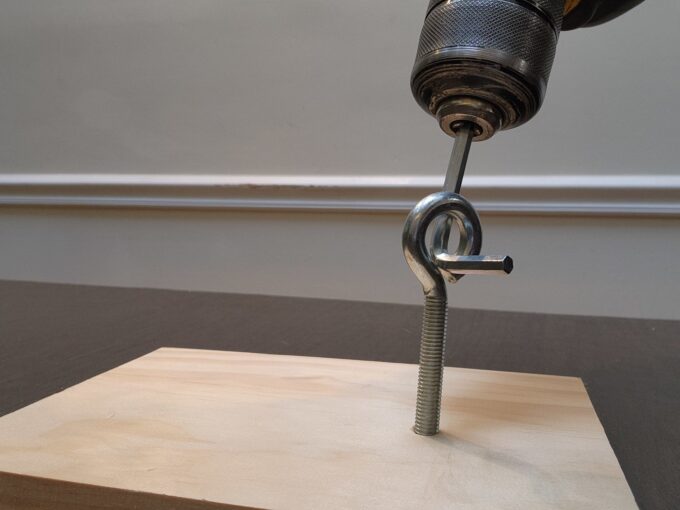 A person using a drill press and a hand saw to cut a curved line.