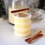 "Homemade eggnog in a glass, garnished with nutmeg and cinnamon stick"
