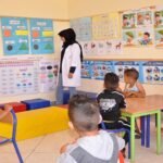 Enfants dans une classe de préscolaire au Maroc, avec un enseignant qui leur enseigne à lire et à écrire.