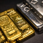 Gold bars and silver coins on a background of a stock market chart