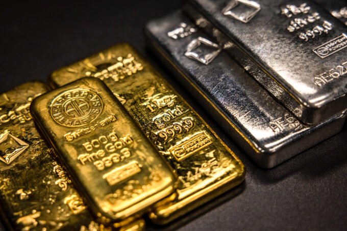Gold bars and silver coins on a background of a stock market chart