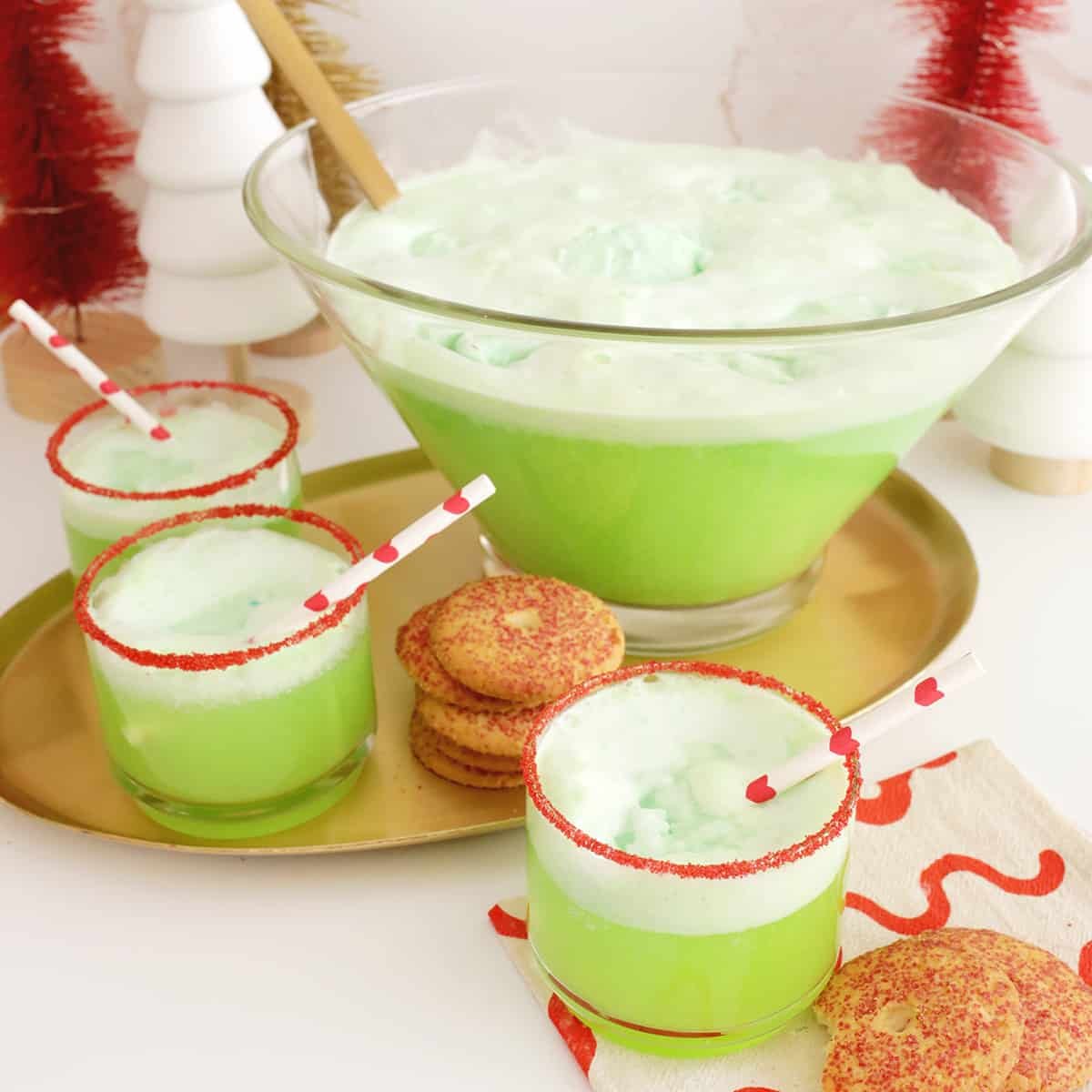 Vibrant green Grinch Punch with scoops of lime sherbet floating, garnished with a red sugar rim, in a festive punch bowl.