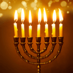 A menorah with candles lit, surrounded by traditional Hanukkah foods.