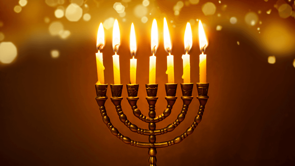 A menorah with candles lit, surrounded by traditional Hanukkah foods.