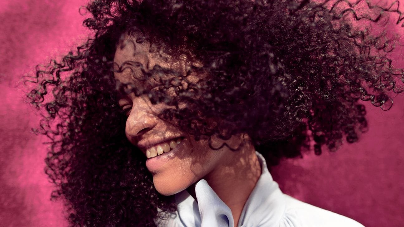 Jojoba oil bottle with hair in the background