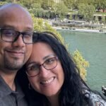 A couple sitting on a sofa, one reading quietly, the other engaged in conversation, symbolizing balance and compromise in a relationship.