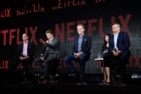 Netflix logo with a debt clock in the background