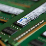 Alt text: A person holding a laptop with a concerned expression, with a graph showing increasing RAM prices in the background.