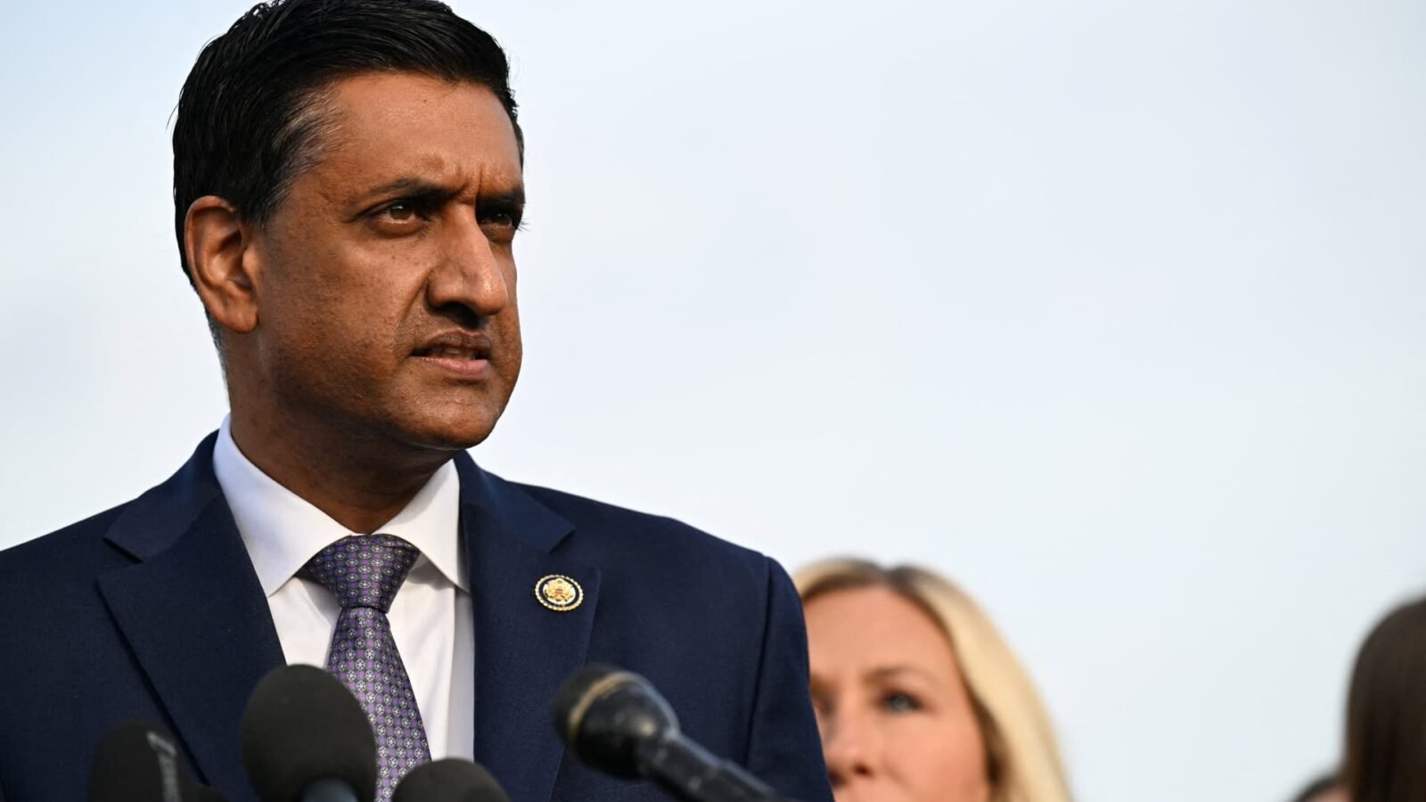 Representative Ro Khanna speaking, with a backdrop subtly hinting at Silicon Valley or a tech-related theme, symbolizing the conflict over the proposed wealth tax.