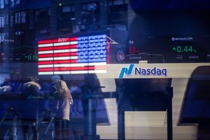 A financial professional examining market data on a screen, with a blurred cityscape in the background representing major financial institutions.