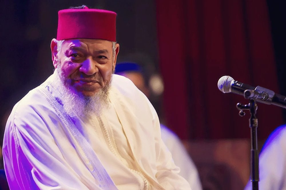 Portrait en noir et blanc d'Abdelhadi Belkhayat, le chanteur marocain, souriant et regardant au loin.