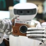 A robot wearing a cowboy hat at CES 2026, attempting to hand over an item, symbolizing AI's presence and occasional stumbles at the event.