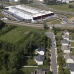 Senator Bernie Sanders and Governor Ron DeSantis, representing opposing political views, stand together against a backdrop of data center infrastructure, symbolizing their unexpected alliance against the AI industry's energy demands.
