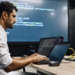 A software developer looking frustrated while working on a computer, with AI-related graphics overlaid.