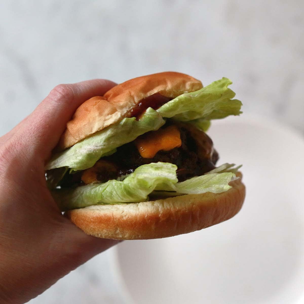 Delicious air fryer hamburger with melted cheese, lettuce, and tomato on a toasted bun.