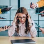 A person looking stressed at a desk while others enjoy vacation, symbolizing the reluctance to take time off.