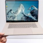 A sleek, thin Asus Zenbook A16 laptop in an earthy beige color, showcasing its large OLED display.