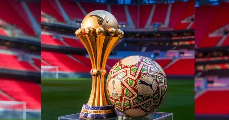 Le ballon officiel ITRI de la CAN 2025, de couleur dorée, posé sur un terrain de football, avec les logos de la CAF et Puma, symbolisant la finale Maroc-Sénégal.