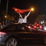 Foule marocaine en liesse célébrant la qualification des Lions de l'Atlas pour la finale de la CAN-2025, drapeaux et chants patriotiques.