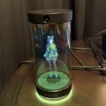 A futuristic USB tube projecting an animated character, representing Razer's Project AVA, alongside a sleek gaming headset with integrated brain-sensing technology.