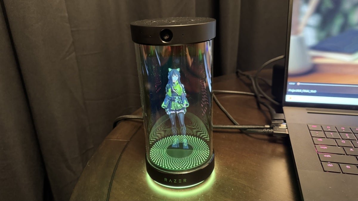 A futuristic USB tube projecting an animated character, representing Razer's Project AVA, alongside a sleek gaming headset with integrated brain-sensing technology.