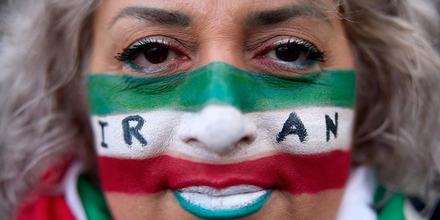 L'ayatollah Ali Khamenei s'exprimant, avec en arrière-plan des images des manifestations en Iran, symbolisant la tension politique.