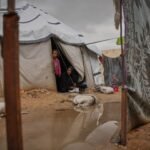 امرأة فلسطينية تطهو الطعام خارج خيمتها بعد أن غمرتها الأمطار في مخيم النصيرات بقطاع غزة.