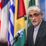 علم إيران وخلفه أعلام الولايات المتحدة وإسرائيل في سياق توترات جيوسياسية