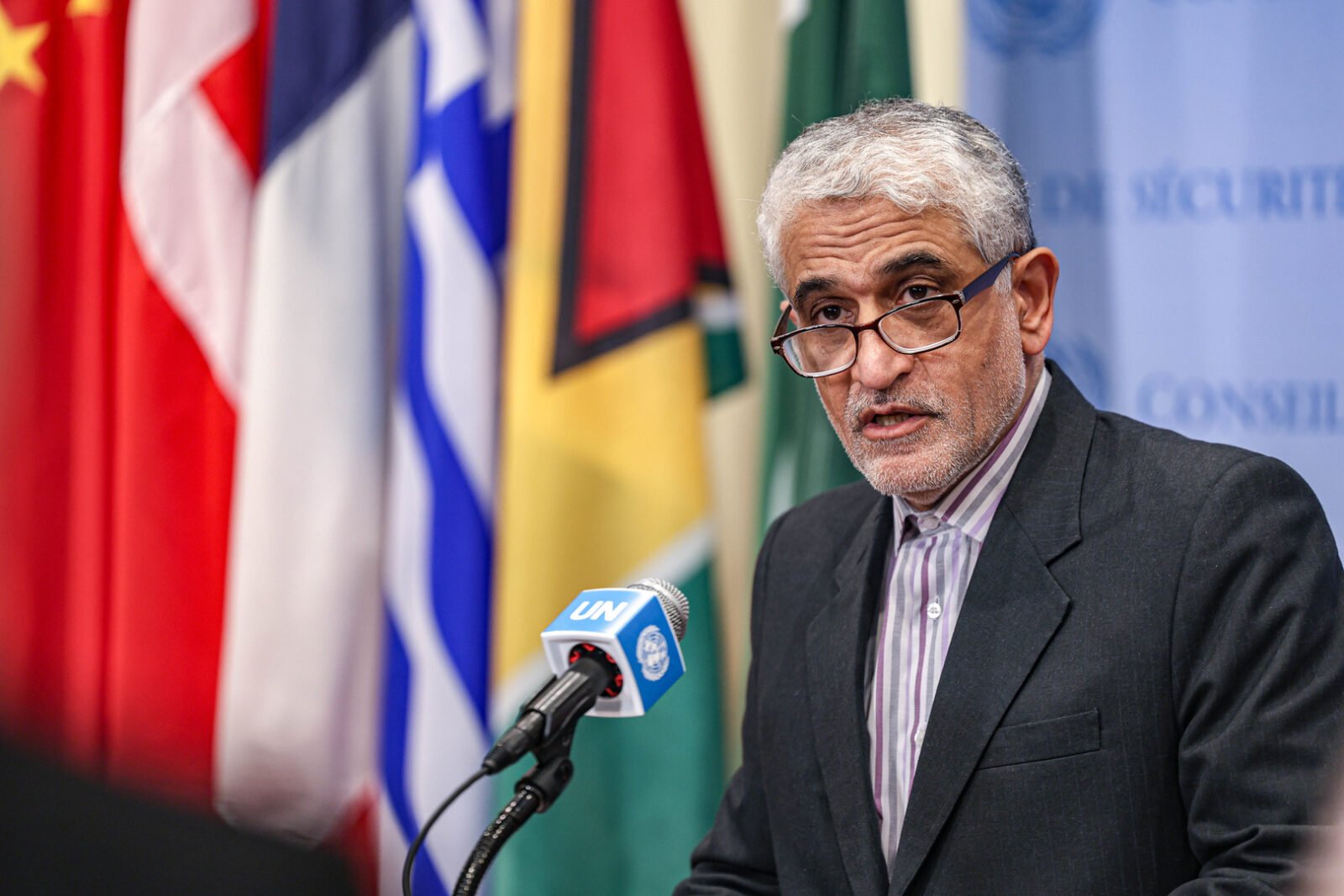 علم إيران وخلفه أعلام الولايات المتحدة وإسرائيل في سياق توترات جيوسياسية