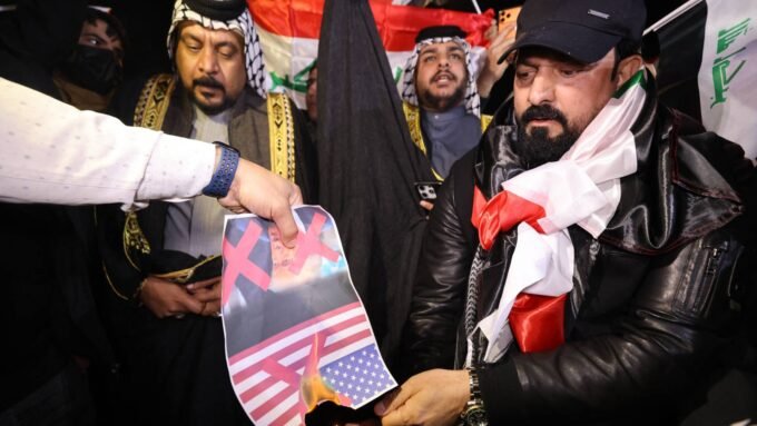 متظاهرون عراقيون يحرقون صورة للرئيس الأمريكي دونالد ترمب قرب السفارة الأمريكية في بغداد.