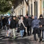 متظاهرون إيرانيون يمرون بمتاجر في طهران تعكس تدهور قيمة الريال وارتفاع الأسعار.