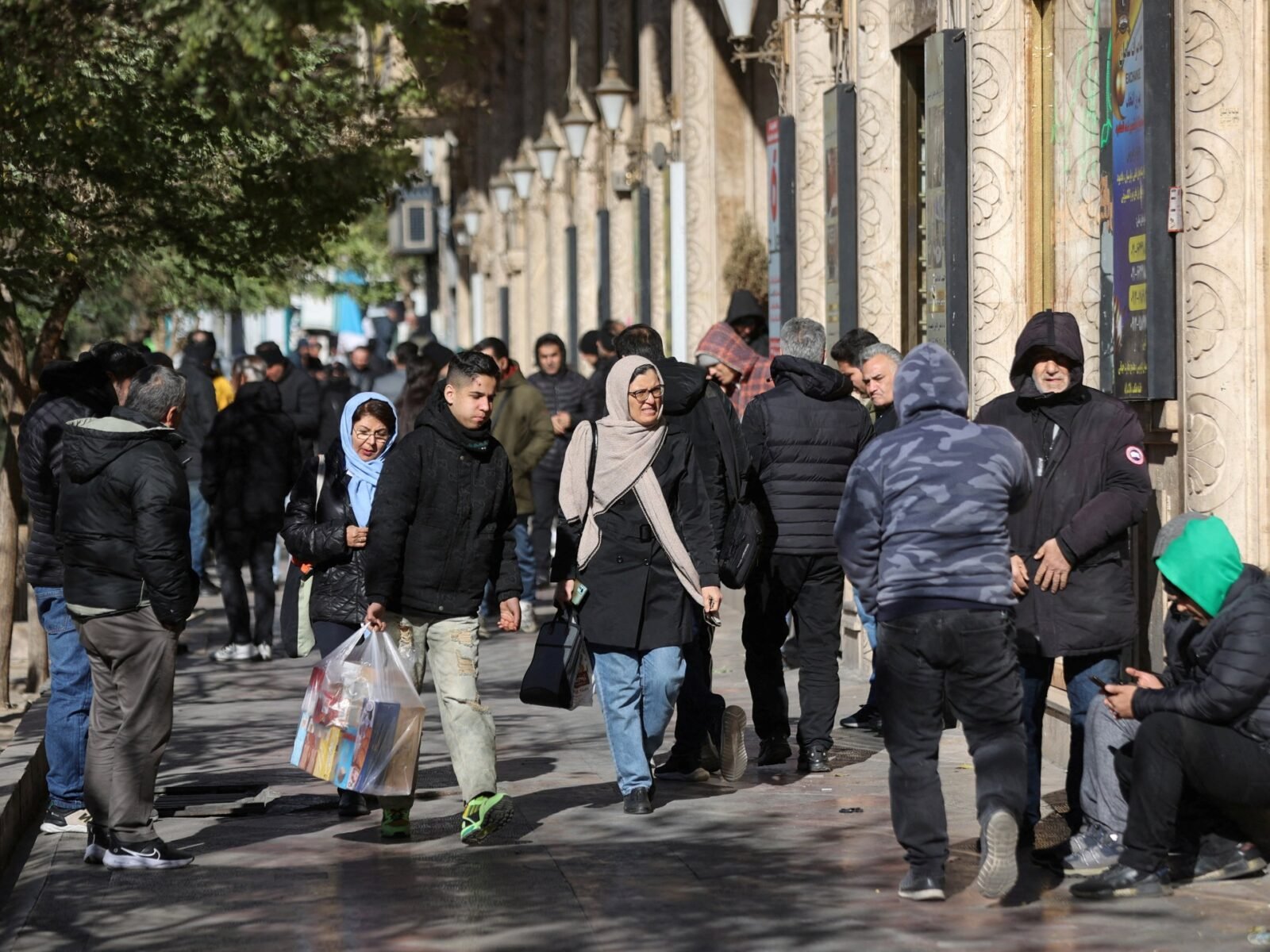 متظاهرون إيرانيون يمرون بمتاجر في طهران تعكس تدهور قيمة الريال وارتفاع الأسعار.