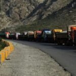 شاحنات بضائع متوقفة عند معبر طورخم الحدودي بين أفغانستان وباكستان، ترمز للتحديات التجارية.