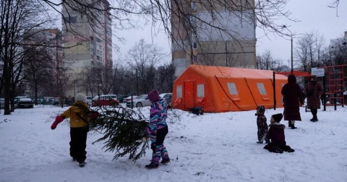 أطفال أوكرانيون يلعبون قرب خيمة لتوفير الطاقة والدفء في كييف بعد الهجمات الروسية.