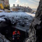 مقيم يشير إلى سقف مبنى سكني في كييف تضرر جراء هجوم بطائرة مسيرة روسية.