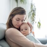 أم ترضع طفلها بابتسامة، تعكس السعادة والترابط بينهما