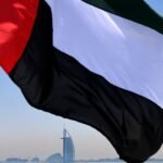 علم الإمارات يرفرف مع خلفية لسماء صافية، يرمز إلى الحياد والسلام الإقليمي.