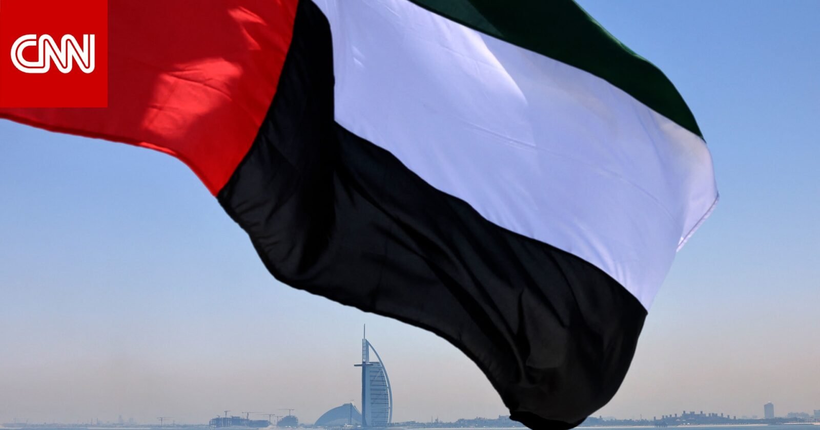 علم الإمارات يرفرف مع خلفية لسماء صافية، يرمز إلى الحياد والسلام الإقليمي.