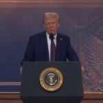 الرئيس الأمريكي دونالد ترامب يوقع وثيقة أمام علم الولايات المتحدة