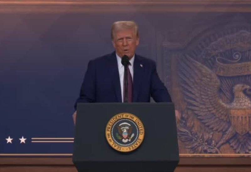 الرئيس الأمريكي دونالد ترامب يوقع وثيقة أمام علم الولايات المتحدة